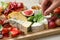 Woman taking basil from board with different appetizers, closeup