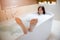 Woman taking bath with her feet on the edge of the bathtub