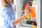 Woman taking bottle with juice out of refrigerator