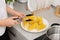 Woman taking corn cob from plate with tong