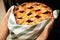 Woman taking freshly baked cherry pie out of oven, closeup