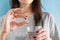 Woman taking gastritis, stomach ulcer, heartburn medicine capsule or pill on blue background with glass of water