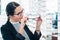 Woman taking glasses off shelf in optician shop