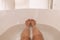 Woman taking a hot bath selfie in tub home cozy relaxation in winter night. POV of feet and legs in water