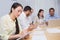 Woman taking notes while colleagues are talking behind her