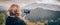 Woman taking panoramic picture of mountain landscape. Selfie photo stick