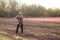 Woman taking phone picture standing in a field of early spring flowers against a blurred background