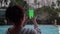 Woman taking picture with green screen in smart phone at resort swimming pool in the evening.