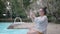 Woman taking picture in smart phone at resort swimming pool in the evening.
