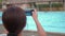 Woman taking picture by smartphone of resort swimming pool.