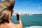 Woman taking pictures with mobile phone in the island of Venice in Italy on a sunny day while traveling on a boat. Traveler.