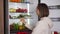 Woman taking raw food from refrigerator. Refrigerator full of healthy food. fruits and vegetables.