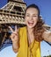 Woman taking selfie and showing victory against Eiffel tower