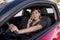Woman talking happy on mobile phone while holding car steering wheel driving distracted