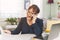 Woman talking and laughing on the phone while checking work documents - Mature woman working from home on the computer - Remote