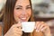 Woman tasting a coffee from a cup in a restaurant terrace