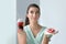 Woman with tasty doughnut and fresh fruits in plastic cup indoors. Choice between healthy and unhealthy food