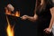 Woman with tattooed hands, dressed in leggings and t-shirt. Holding burning wok pan above fire and frying two beef