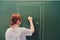 Woman teacher knocks on the door drawn in chalk on the blackboard. Concept of online education in schools