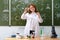 Woman teacher looks at the chemical reaction liquid in a bottle. Scientific experiments in a school chemistry class