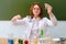 Woman teacher looks at the chemical reaction of a reagent in a flask. Scientific experiments in a school chemistry class