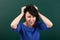 Woman teacher in stress posing by chalk Board, tears her hair, learning concept, green background, Studio shot