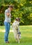 Woman teaching adorable smart dog Australian Shepherd new commands during obedience training in nature