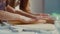 Woman teaching girl to roll dough on kitchen table. Girl hands using rolling pin