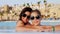 Woman and teen girl, mom and daughter, in funny, identical, round sunglasses, relax, have fun in outdoor pool with