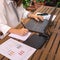 Woman teleworking in the garden of her house and writing down notes in a notebook,