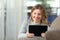 Woman thinking holding a tablet at home