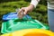 Woman throwing glass bottle into recycling bin outdoors, closeup