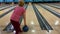 Woman throws a blue bowling ball along the track.