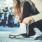 Woman tie shoelaces figure skates at ice rink close-up