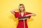 Woman tired of household chores headache. Overworking. Blonde girl in red dress, yellow background. With broom in hand.