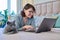 Woman together with cat lying on bed at home, female using laptop
