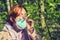 A woman took off her medical mask after being quarantined near a tree with green leaves