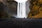 Woman at the toot of an Impressive Waterfall in autumn