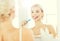 Woman with toothbrush cleaning teeth at bathroom