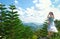 Woman on top of Khao Kho Mountain in Thailand with views of pine trees and mountains.