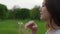 Woman touch fingers flower on dandelion seed head and blow, floret fly away