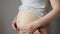 Woman touches fat on flabby sagging belly after pregnancy