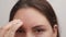 woman touches her forehead with one hand. It is very flaky and causes discomfort