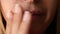 Woman touches the sores from herpes on her lips. Women`s lip ulcers herpes closeup. Beautiful lips were covered with