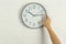 Woman touching clock on white brick wall.