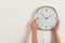 Woman touching clock on white brick wall, space for text