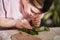 Woman touching with the finger fresh leaf while imprinting texture of it to the clay