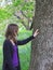 Woman touching oak tree trunk