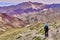 Woman tourist with a backpack climbing steep slope with beautiful colorful Himalaya mountains in the background, Ladakh, India