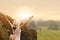 Woman tourist with backpack enjoying valley view with arms up from top of a mountain with sunset